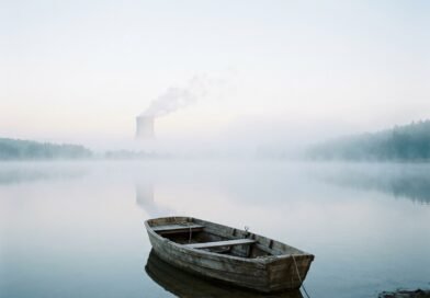 Wooden rowing boat on a misty Czech lake with a distant cooling tower, representing Temelín SMR environmental review